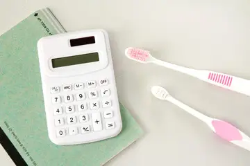電卓と歯ブラシ、ノート。歯科治療の費用・お支払いのイメージ